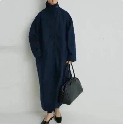 Woman in navy blue oversized coat with high collar, carrying black tote bag, stylish fashion look