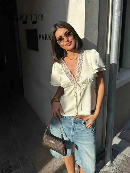 Woman in white lace-trim blouse and denim shorts, stylish streetwear fashion