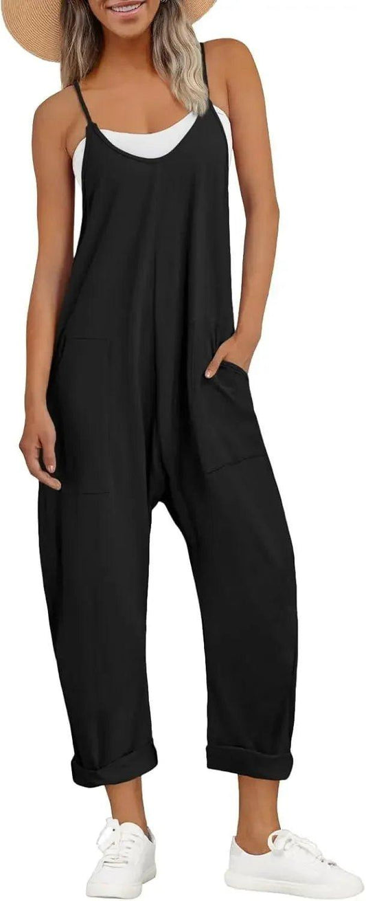Woman wearing black sleeveless jumpsuit with pockets, white sneakers, and straw hat for summer fashion