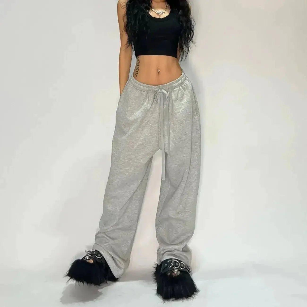 Woman in black crop top, gray sweatpants, and fuzzy black sandals for casual fashion