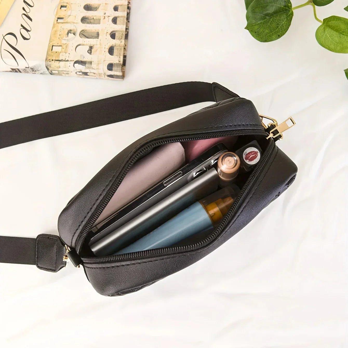 Black women's crossbody bag with gold zipper, holding phone, lipstick, and essentials on white background