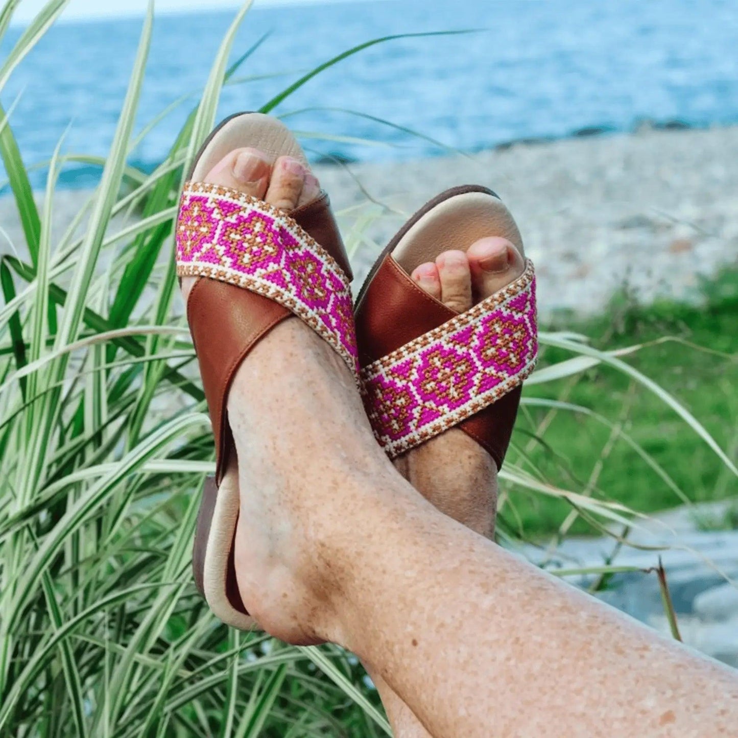 Women's brown sandals with pink embroidered straps, beachside fashion footwear
