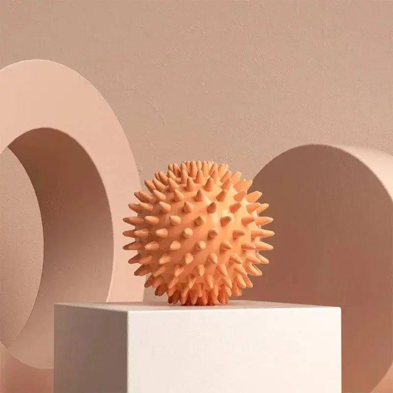 Spiky orange massage ball on white pedestal, minimalist beauty & wellness product display