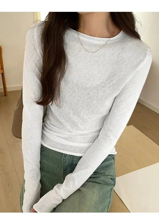 White long sleeve women's fashion top with layered design, paired with green jeans for casual style