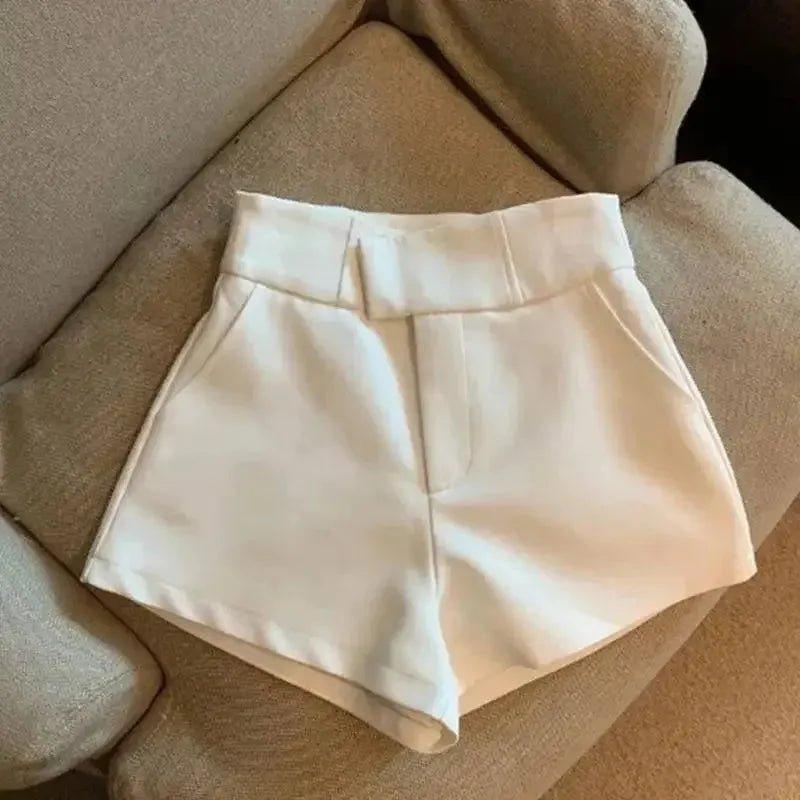 White high-waisted women's fashion shorts on beige sofa