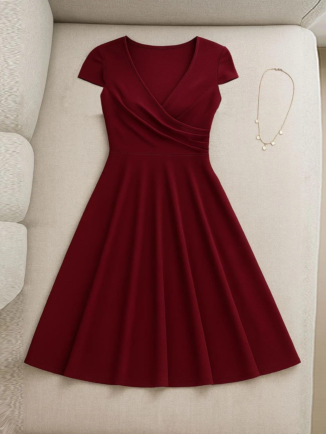 Burgundy V-neck wrap dress with short sleeves and flared skirt, styled with gold necklace on beige sofa