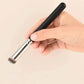 Hand holding black-handled makeup brush with silver ferrule for face or eye application