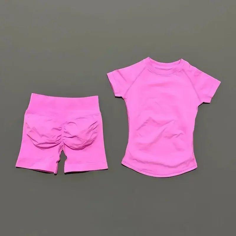 Pink women's activewear set with ruched shorts and short-sleeve top, perfect for gym or yoga