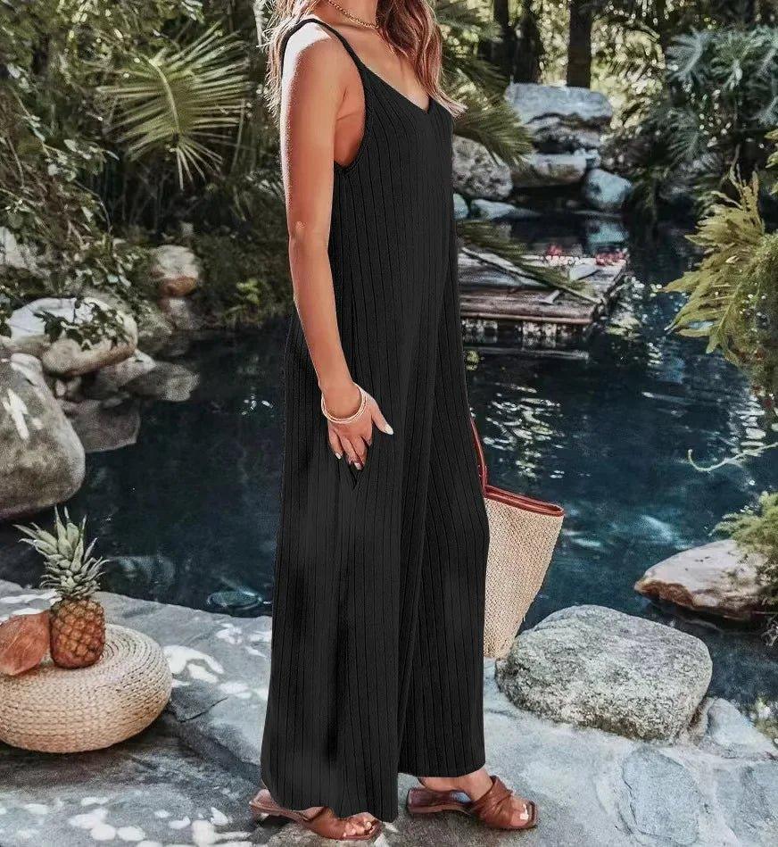 Woman in black ribbed jumpsuit by poolside, summer fashion outfit with woven bag and sandals