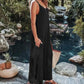 Black ribbed sleeveless jumpsuit for women, stylish summer outfit by poolside with woven bag and sandals