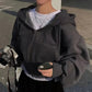 Woman wearing cozy gray zip-up hoodie with white tee, holding camera and phone, street style fashion