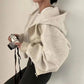 Woman in cozy beige zip-up hoodie holding camera, stylish streetwear fashion