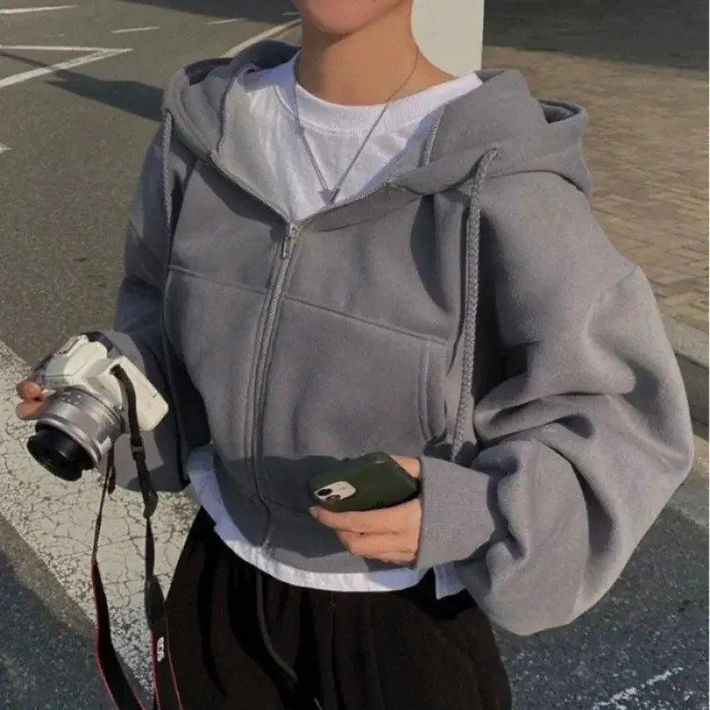 Gray zip-up hoodie with white tee, styled for women's casual fashion, holding camera and phone