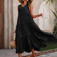 Woman in black tiered midi dress, straw hat, sunglasses, and woven bag, walking outdoors