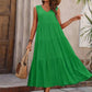 Woman in green tiered maxi dress, straw hat, and woven bag for summer fashion