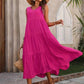 Woman in vibrant pink tiered maxi dress, straw hat, and sandals for summer fashion