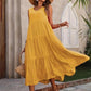 Woman in yellow tiered midi dress, straw hat, and sandals for summer fashion