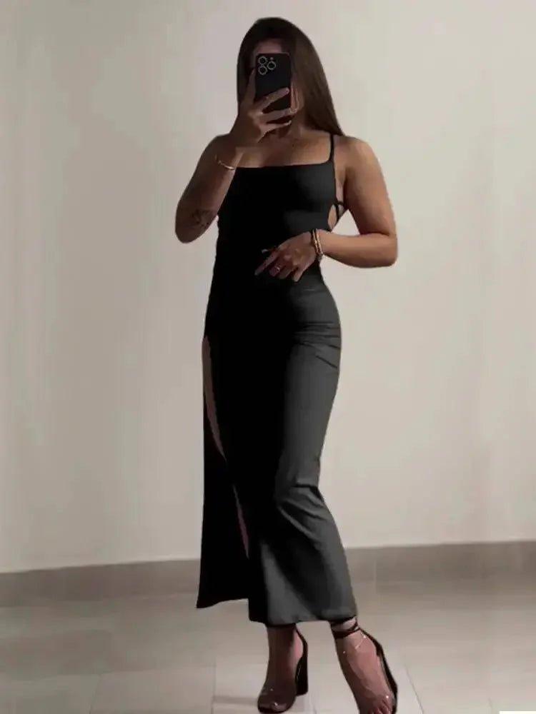 Woman in black spaghetti strap dress with side slit, taking mirror selfie, fashion outfit
