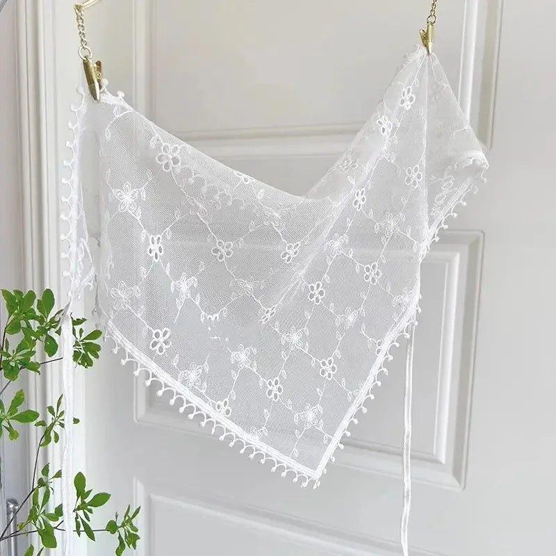 White lace triangle scarf with floral embroidery, delicate pom-pom trim, hanging on door for women's fashion