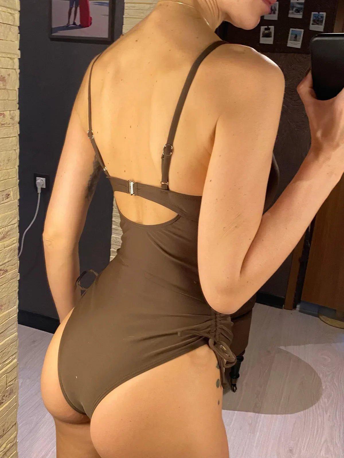 Woman in olive green one-piece swimsuit with adjustable straps and side ruching, back view