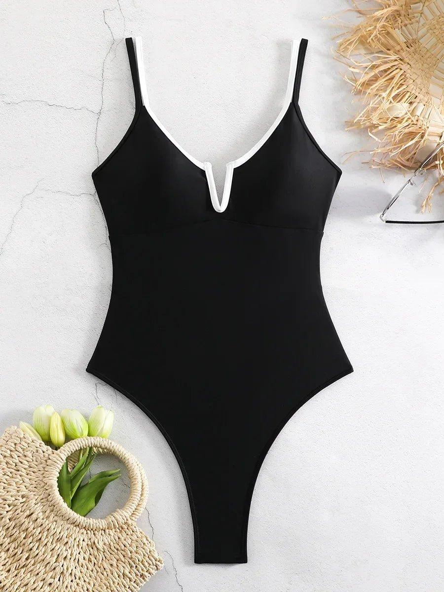 Black one-piece swimsuit with white trim, styled with straw bag and tulips for beach fashion