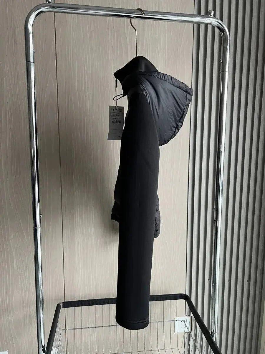 Black women's hooded puffer coat on clothing rack, stylish winter fashion outerwear