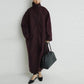 Woman in burgundy oversized coat with black bag and heels, modern fashion look
