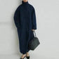 Woman in navy blue oversized coat with high collar, carrying black tote bag, stylish fashion look
