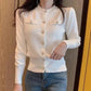 White women's cardigan with decorative buttons, long sleeves, and ribbed hem, paired with jeans