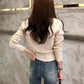 Woman in cream knit sweater and high-waist jeans, back view fashion outfit