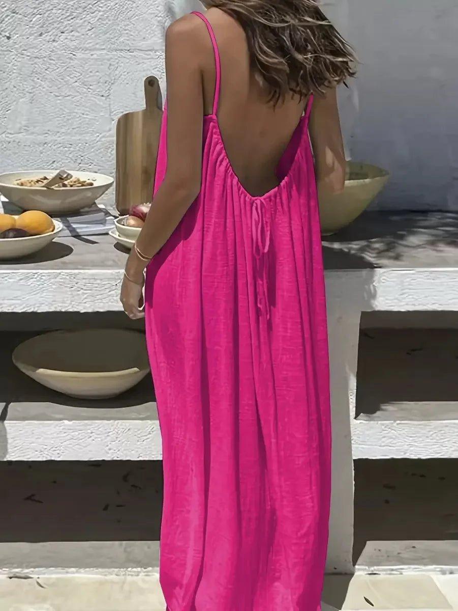 Woman in vibrant pink backless maxi dress, summer fashion, beach style, casual elegance