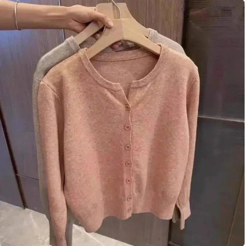 Soft pink women's cardigan sweater with button front, cozy knit, long sleeves, displayed on hanger