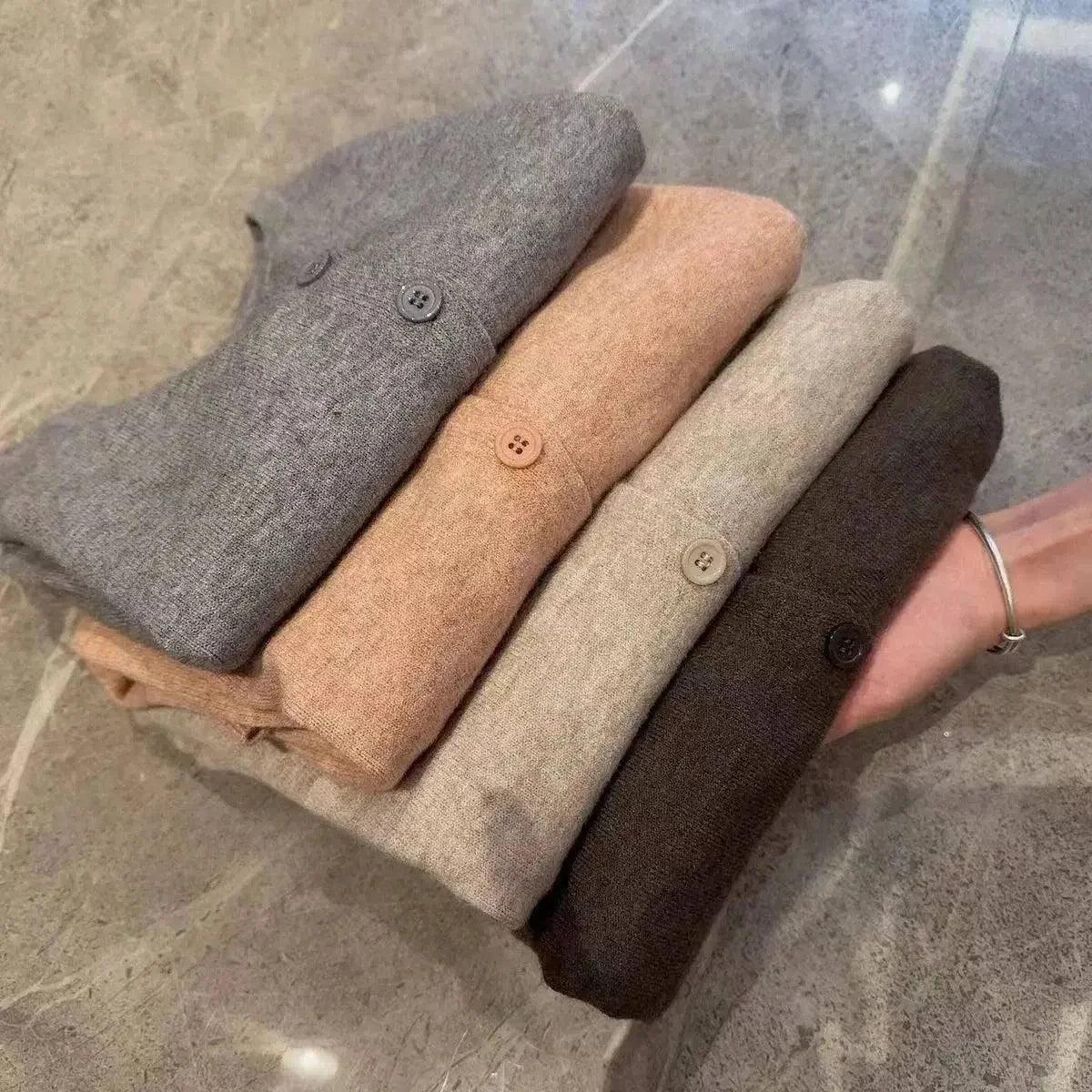 Folded women's button-up sweaters in gray, beige, cream, and brown tones