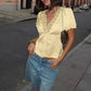 Woman in yellow lace-trim blouse and denim shorts, street fashion style