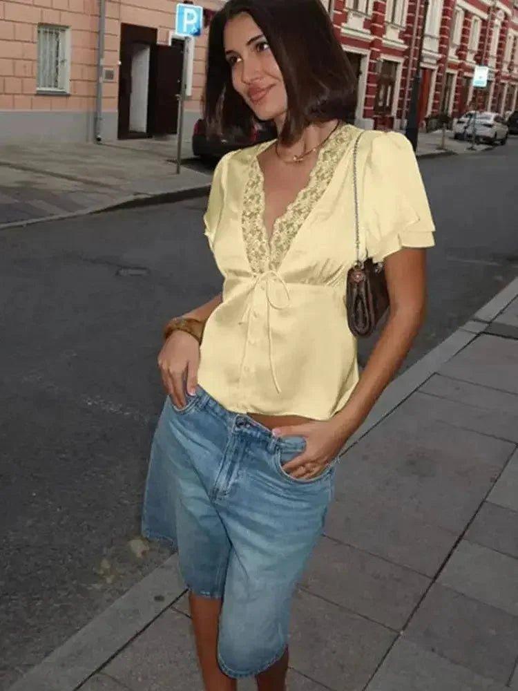 Woman in yellow lace-trim blouse and denim shorts, street fashion style