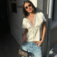 Woman in white lace-trim blouse and denim shorts, stylish streetwear fashion
