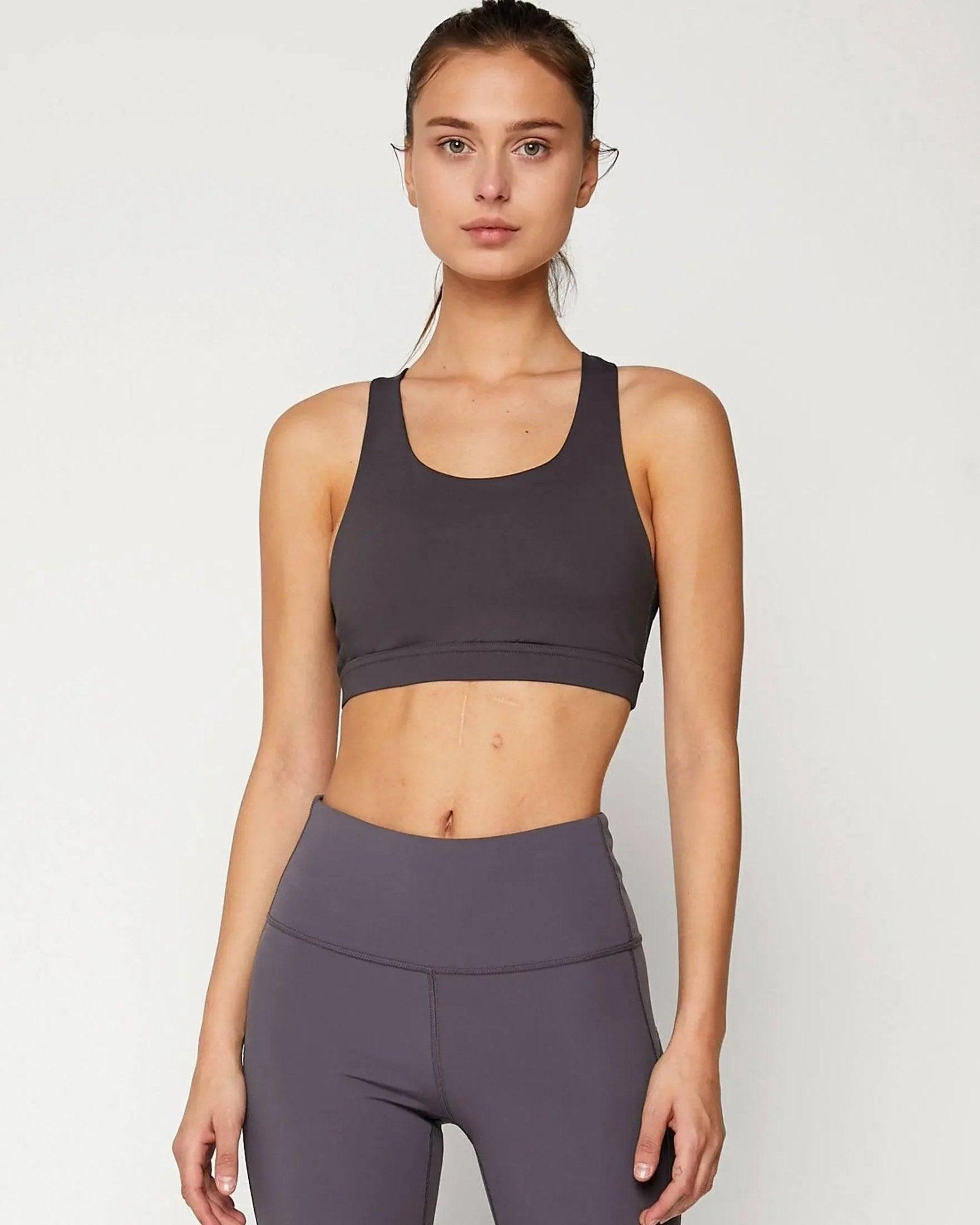 Woman in gray sports bra and high-waisted leggings, fitness apparel for gym or yoga