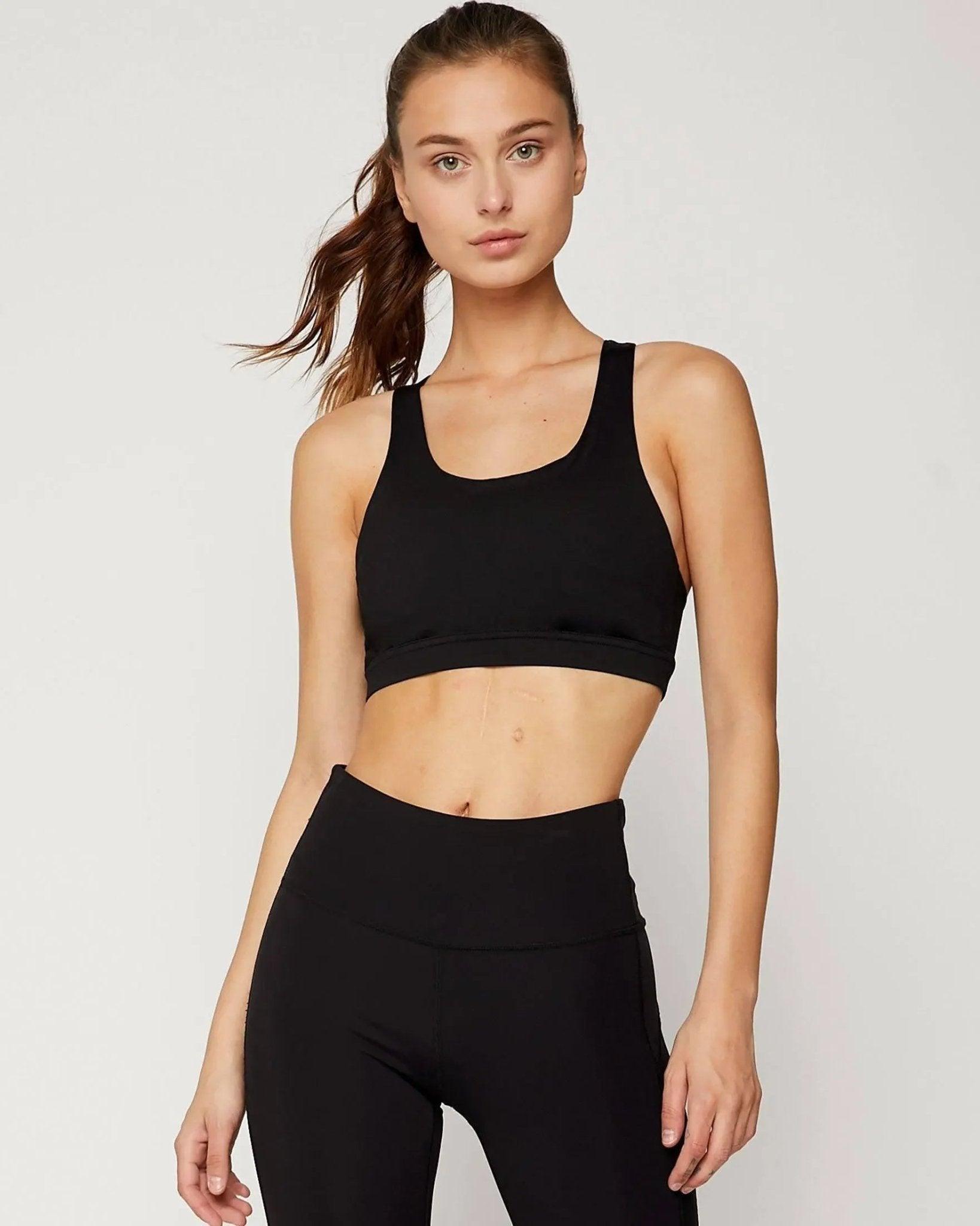 Woman in black sports bra and high-waist leggings, fitness activewear for gym or yoga
