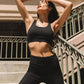 Woman in black sports bra and leggings posing on stairs, fitness fashion