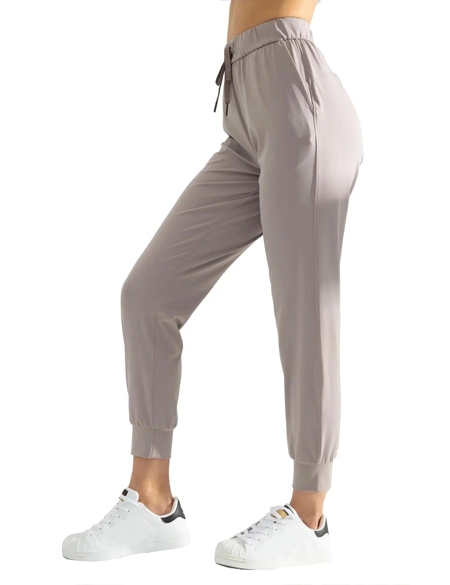 Women's gray jogger pants with drawstring waist, elastic cuffs, paired with white sneakers for casual fashion