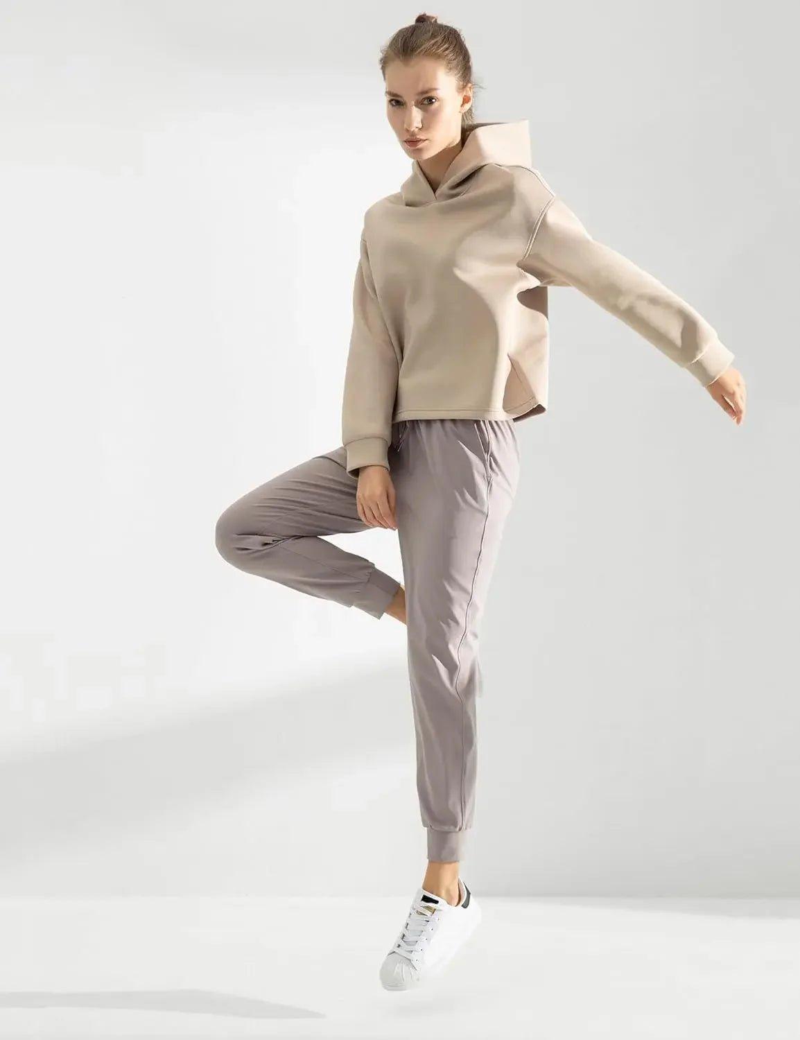 Woman in beige cropped hoodie and gray joggers, stylish athleisure outfit for casual wear