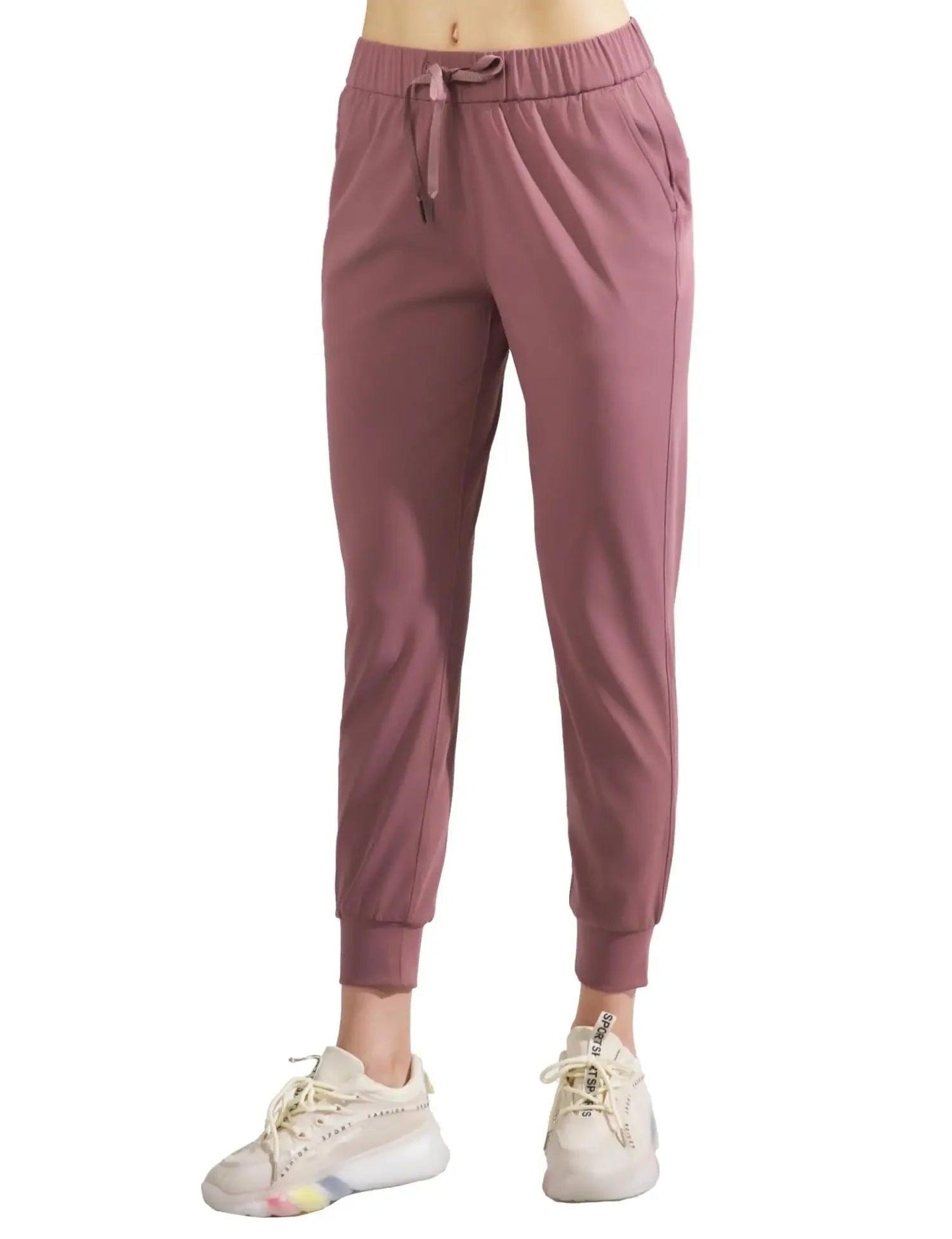 Women's mauve jogger pants with drawstring waist, elastic cuffs, paired with white sneakers for casual fashion