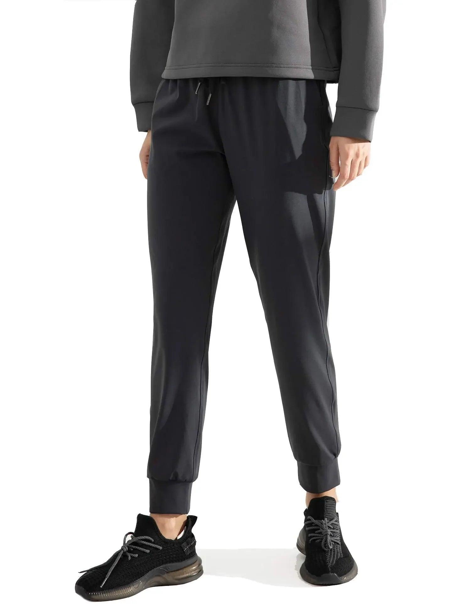 Black jogger pants with drawstring waist, paired with gray hoodie and athletic sneakers for casual fashion