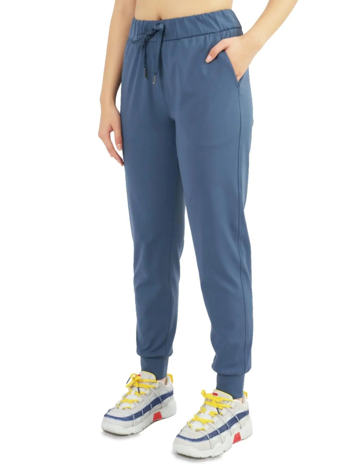 Women's blue jogger pants with drawstring waist, side pockets, and elastic cuffs, styled with colorful sneakers