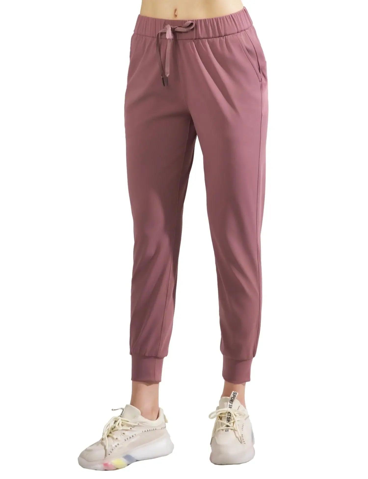 Women's dusty rose joggers with drawstring waist, elastic cuffs, paired with white sneakers for casual fashion.
