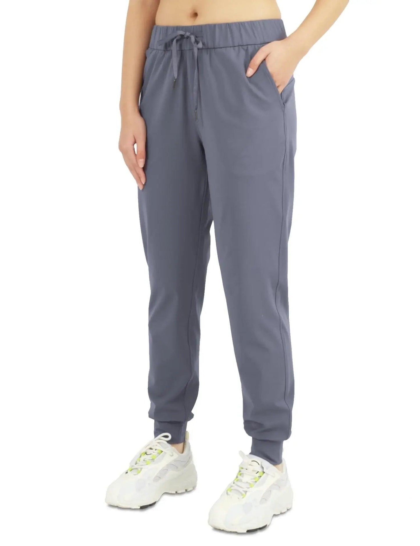 Gray women's jogger pants with drawstring waist, side pockets, and cuffed ankles, paired with white sneakers