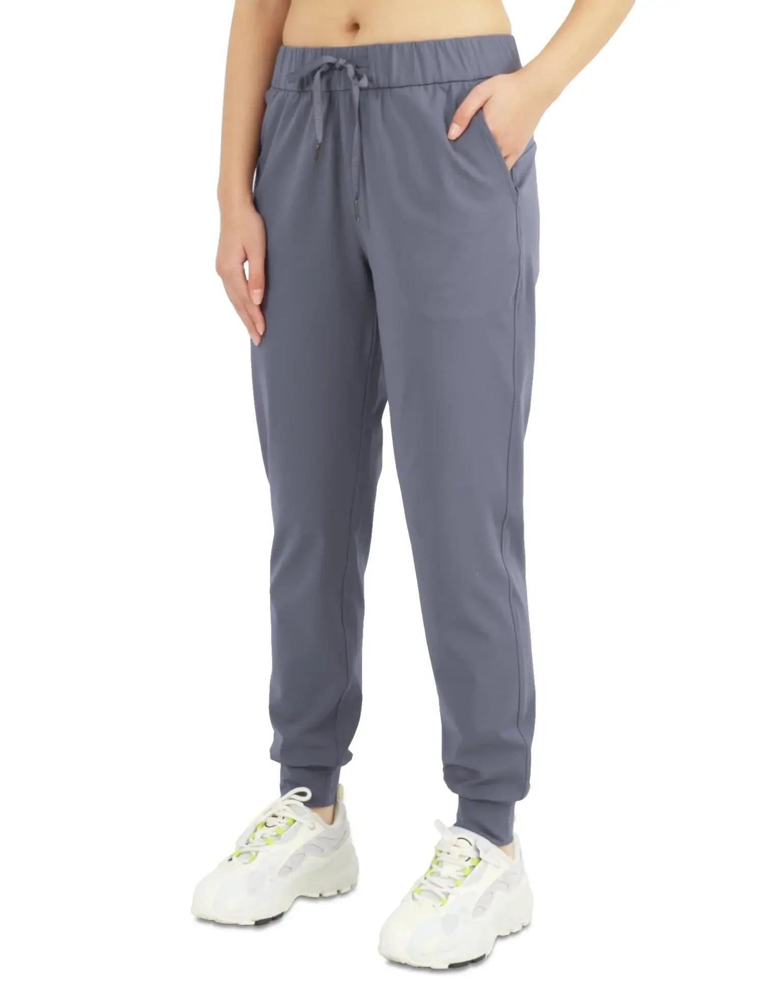 Gray women's jogger pants with drawstring waist, side pockets, and cuffed ankles, paired with white sneakers