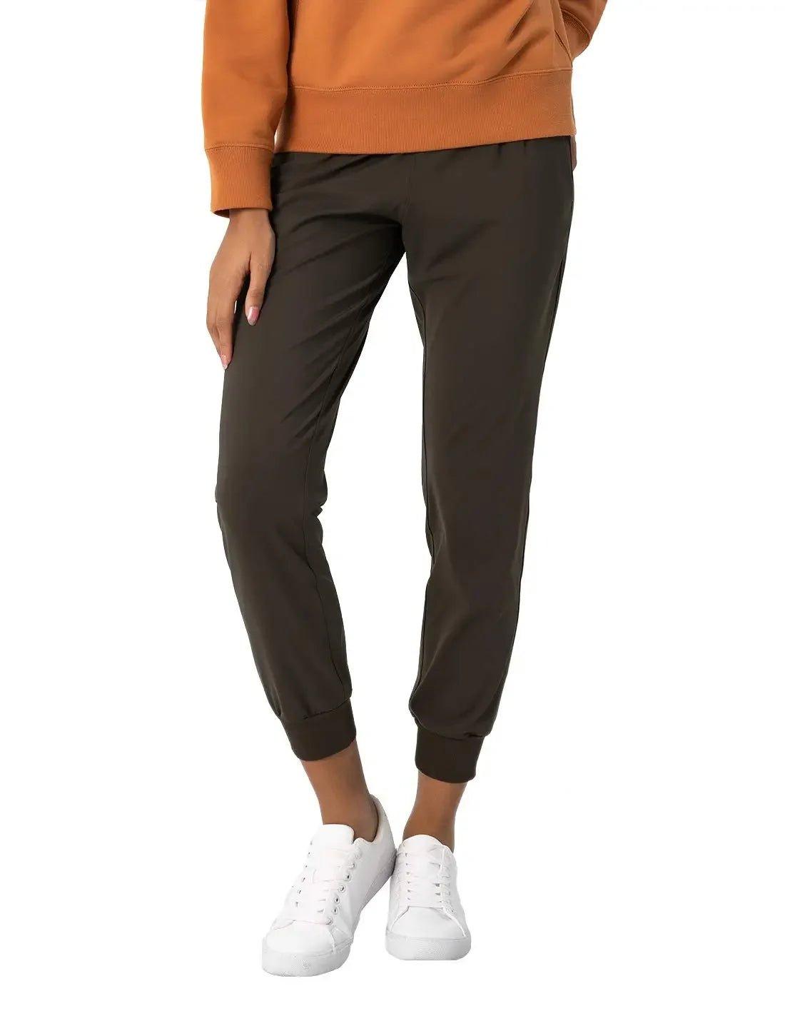 Women's olive green jogger pants with cuffed ankles, paired with white sneakers and an orange hoodie