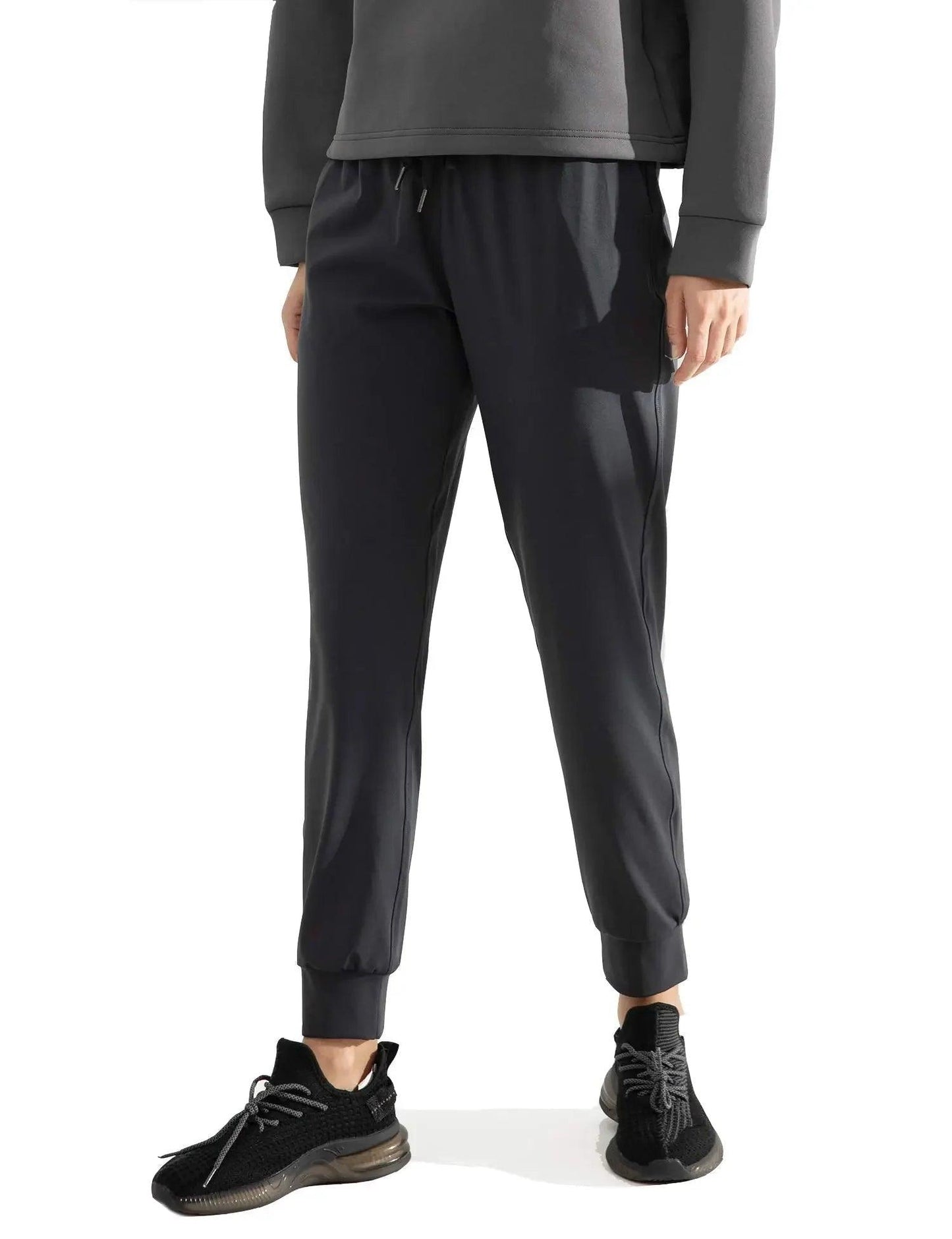 Black jogger pants with drawstring waist, paired with gray hoodie and black sneakers for casual fashion