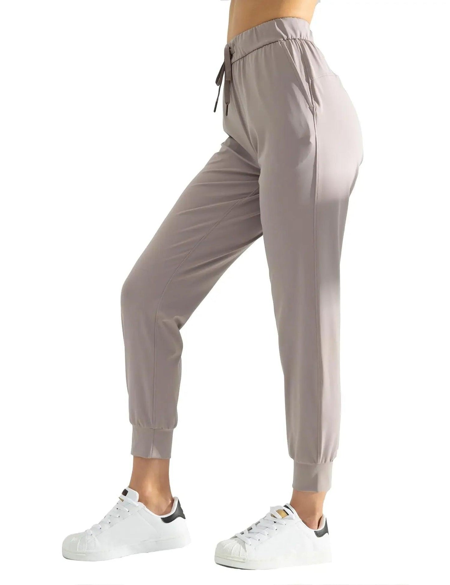 Women's gray jogger pants with drawstring waist, elastic cuffs, paired with white sneakers for casual fashion